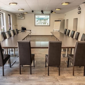 Une salle de conférence équipée d’une longue table, de chaises, d’un écran de projection et d’un tableau blanc.