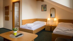 A hotel room with two beds, a wooden ceiling, a bedside table with lamps, a mirror, and a small plant on the table. - Hotel Kanarek (Prague)