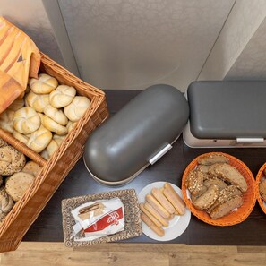 A buffet table with various breads, a loaf of bread, and a package of breadsticks. - Kanarek Hotel (Prague)