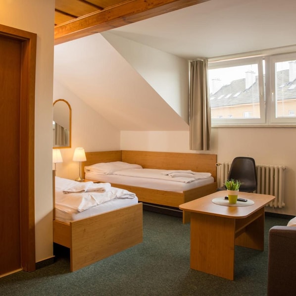 A hotel room with two wooden beds, a desk, a chair, a small potted plant, and a window with curtains. - Hotel Kanarek (Prague)