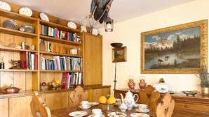 Comedor con una mesa de madera preparada para el té, rodeado de estanterías llenas de libros y objetos decorativos.