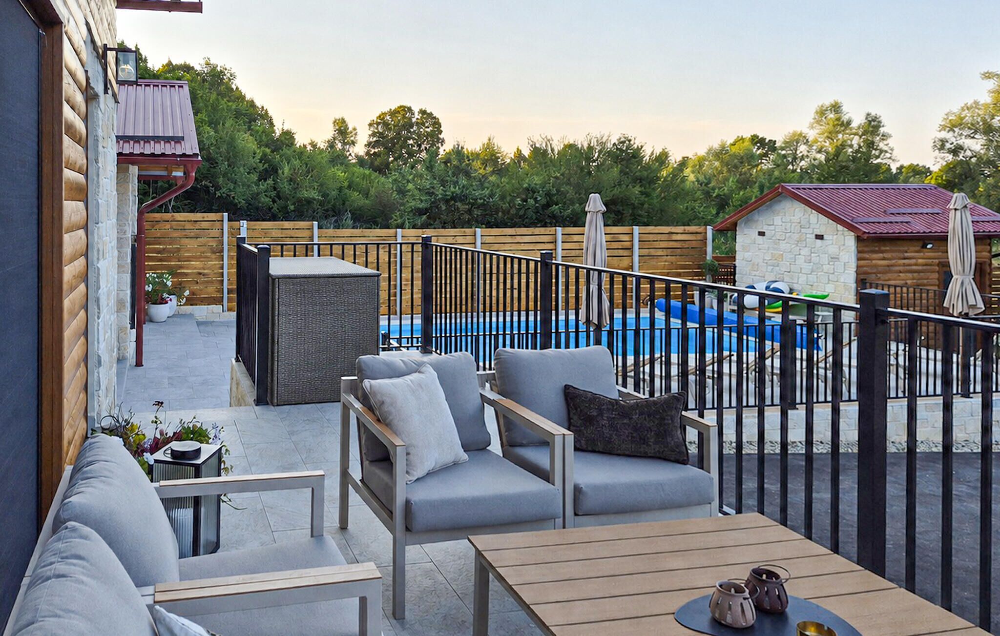 A patio area with outdoor furniture, a pool, and a wooden fence.