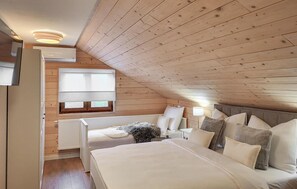 A cozy attic bedroom with a sloped ceiling, a large bed, a window with blinds, and a radiator. - Lovely home in Smiljan with sauna (Smiljan)