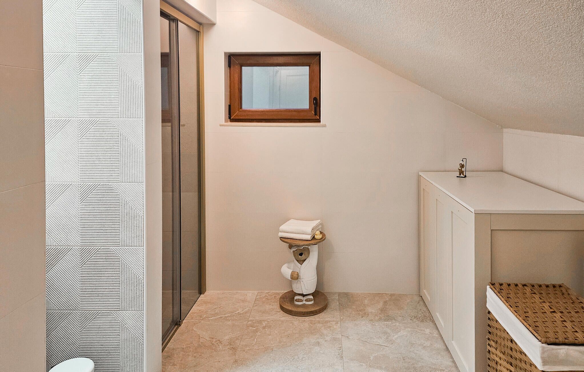A bathroom with a toilet, a small window, a towel rack, and a cabinet.
