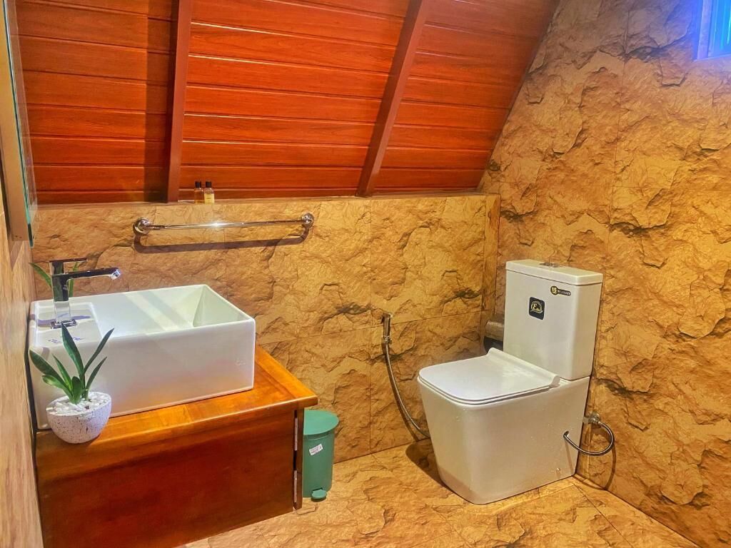 A bathroom with a wooden vanity, a sink, a toilet, and a shower.