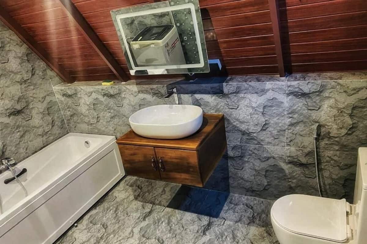 A bathroom with a bathtub, a sink with a wooden vanity, and a toilet.