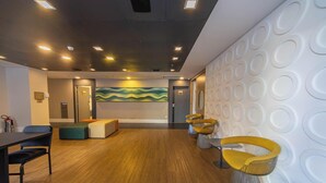 Un intérieur moderne avec un plancher en bois, un coin salon avec des chaises jaunes, une fresque murale colorée et un mur à motifs.