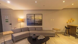 Un salon moderne avec un canapé, une table basse, une lampe et un tableau au mur.