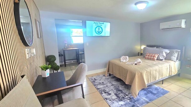 A bedroom with a bed, bedside table, and a desk with a chair. - #15 Guest house Midtown stadium B (Tampa)
