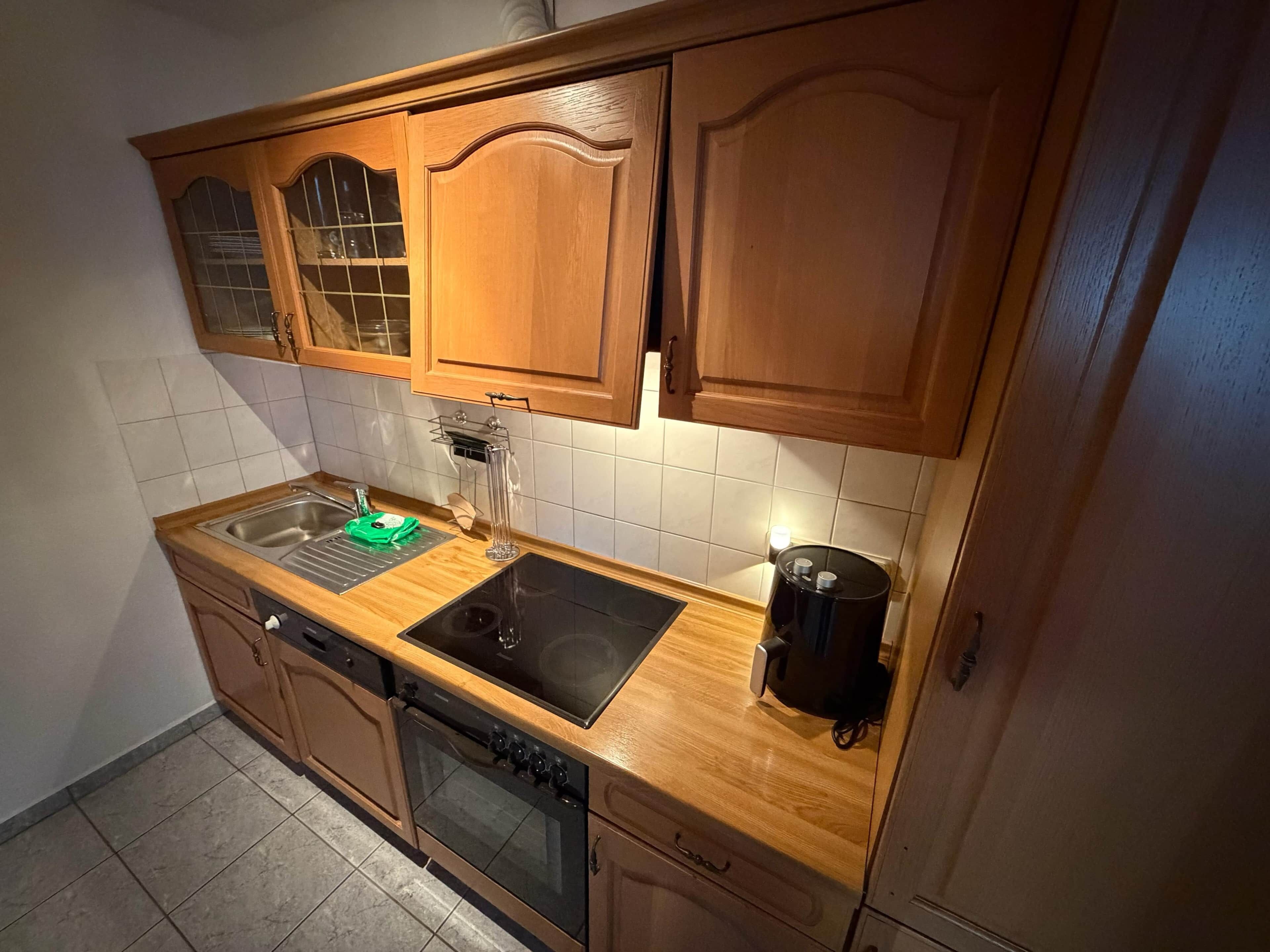 A kitchen with wooden cabinets, a sink, a stove, and a coffee maker.