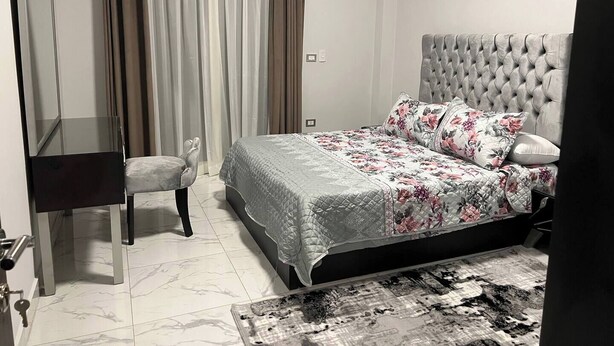 A bedroom with a bed, a chair, a desk, and a mirror. - Elite House: Cozy Garden Oasis 3BR – Mall of Arabia (Giza Governorate)