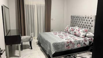 Un dormitorio con cama, silla, escritorio y espejo.