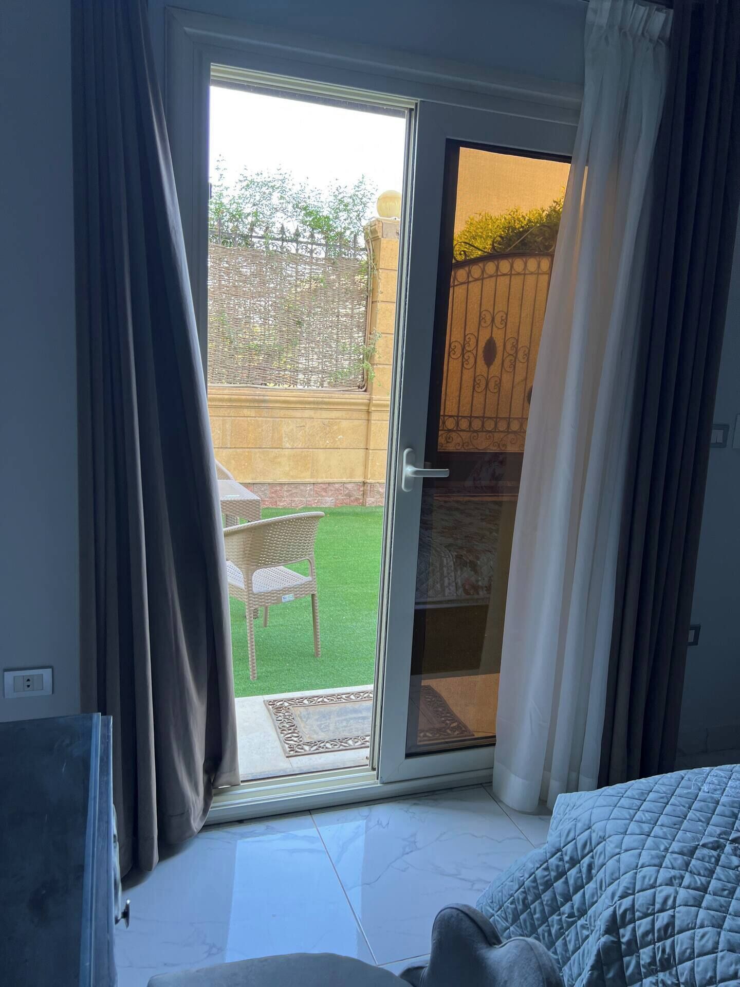 Un dormitorio con una puerta corrediza de vidrio que da a un patio con una silla y una pequeña mesa.
