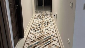 A hallway with a patterned rug, a door on the left, and a light switch on the wall. - Elite House: Cozy Garden Oasis 3BR – Mall of Arabia (Giza Governorate)
