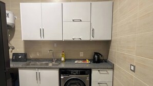 A compact kitchen with a washing machine, a sink, and cabinets. - Elite House: Cozy Garden Oasis 3BR – Mall of Arabia (Giza Governorate)