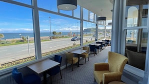 A restaurant with large windows overlooking a road and the sea. - Hydro Hotel (Llandudno)