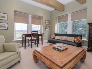 A living room with a sofa, a wooden coffee table, a chair, and a desk with a view of the outdoors. - Daisy Mount (Keighley)