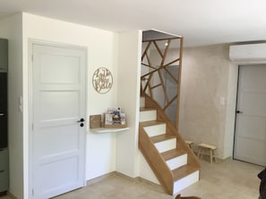 Una escalera con diseño geométrico, una puerta blanca, un estante con libros y un adorno en la pared.