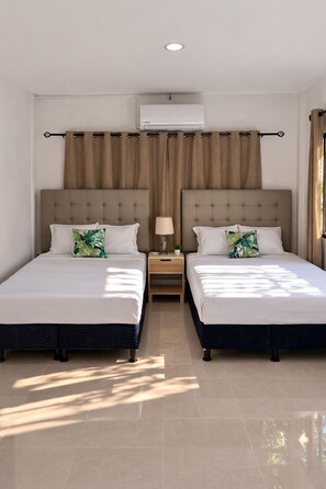 A hotel room with two beds, a nightstand, a lamp, and an air conditioning unit.
