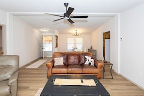 A living room with a brown leather couch, a black coffee table, and a ceiling fan.