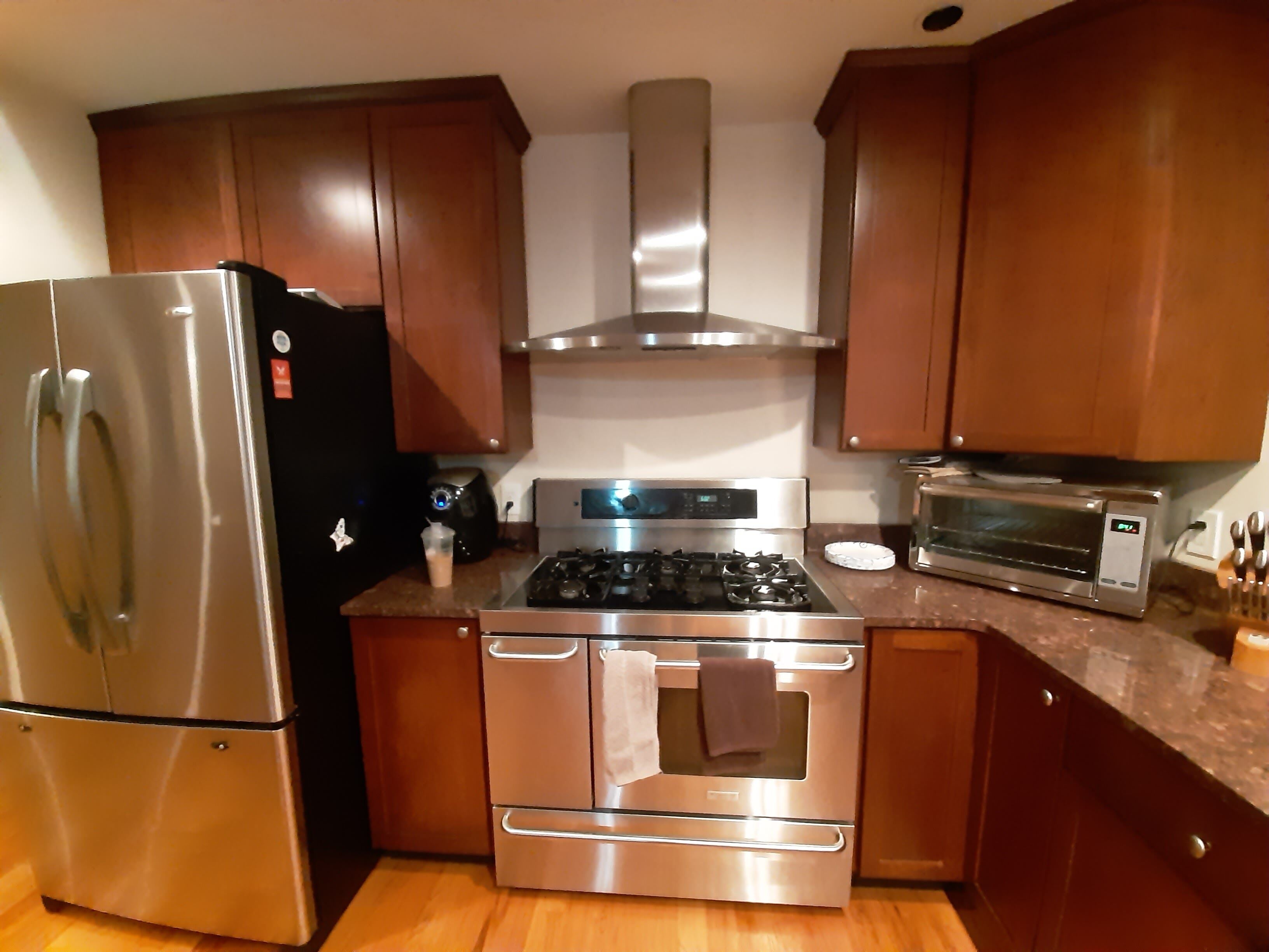 A kitchen with a stainless steel refrigerator, oven, microwave, and a gas stove.