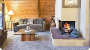 Una sala de estar acogedora con chimenea, paredes de madera, un sofá y una mesa de centro.