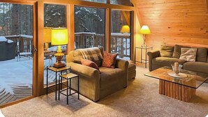 Un interior acogedor con sofá, sillón y mesa de centro, ventanas amplias y techo de madera.