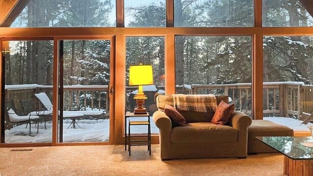 Una habitación espaciosa con techos altos, ventanas amplias, un sofá, una mesita y una lámpara.