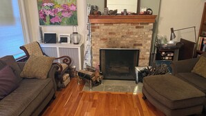 A living room with a fireplace, two sofas, a coffee table, and a painting on the wall. - Spacious 4-bedroom house in beautiful Hoboken. 20 min to Manhattan and Soccer! (Hoboken)