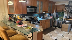 A modern kitchen with wooden cabinets, a glass island, bar stools, a microwave, and a stove. - Spacious 4-bedroom house in beautiful Hoboken. 20 min to Manhattan and Soccer! (Hoboken)