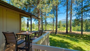 Un espacio de estar al aire libre cubierto con una mesa y sillas, con vistas a un paisaje boscoso.