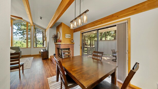 Un comedor con una mesa y sillas de madera, una chimenea y ventanas amplias.