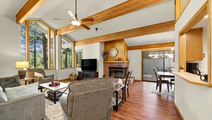 Amplia sala de estar con chimenea, televisor y comedor con mesa y sillas.