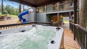 Ein Whirlpool mit Rutsche, eine Holzterrasse und Blick auf die Umgebung.