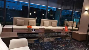 Een moderne lobby met een zithoek, een bijzettafeltje en een marmeren vloer.
