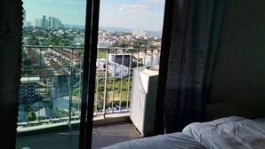 Een hotelkamer met een ruim balkon, een bed en uitzicht op een stadsbeeld.