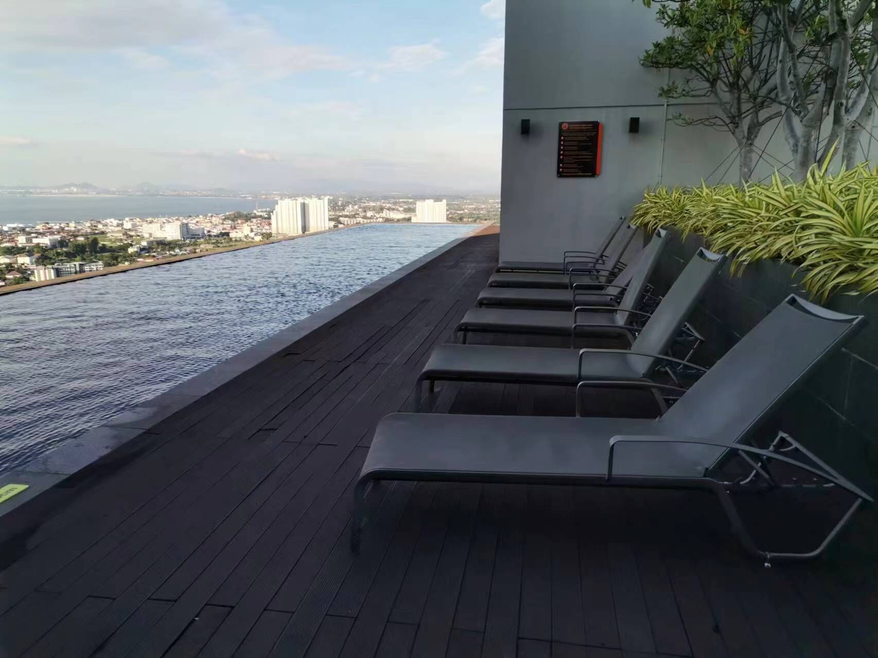 A rooftop pool with lounge chairs and a city view.