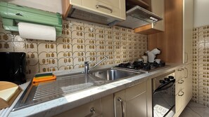 A kitchen with a sink, stove, and cabinets. - Appartamento Belvedere nel cuore della Valtellina (Teglio)