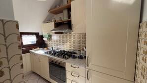 Eine Küche mit Gasherd, Backofen und Spüle. Es gibt Schränke und ein Fenster mit Blick.