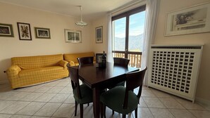 Ein Essbereich mit Tisch und Stühlen, einem gelben Sofa und einem Fenster mit Blick.
