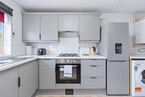 A compact kitchen with a gas stove, oven, refrigerator, and a washing machine. - Charming Flat • Great Location • Free Parking • Fast WiFi • Self-Check-In (Nottingham)