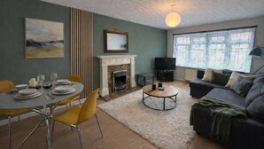 A living room with a fireplace, dining table, and sofa. - Charming Flat • Great Location • Free Parking • Fast WiFi • Self-Check-In (Nottingham)