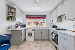 A compact kitchen with a washing machine, microwave, and stove. - Charming Flat • Great Location • Free Parking • Fast WiFi • Self-Check-In (Nottingham)