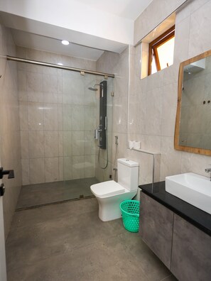 Ein modernes Badezimmer mit einer einteiligen Duschkabine, einer weißen Toilette, einer schwarzen Waschtischplatte und einem Spiegel.