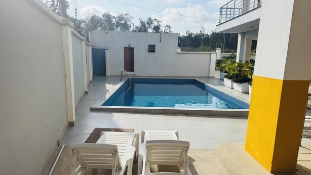 Une piscine avec deux chaises longues, une porte et une petite fenêtre.