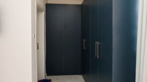 Un couloir avec une armoire sombre, une porte blanche et un sol carrelé.