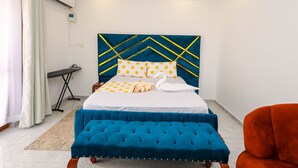 Une chambre d’hôtel bien rangée, avec un lit, une banquette, une chaise et une petite table.