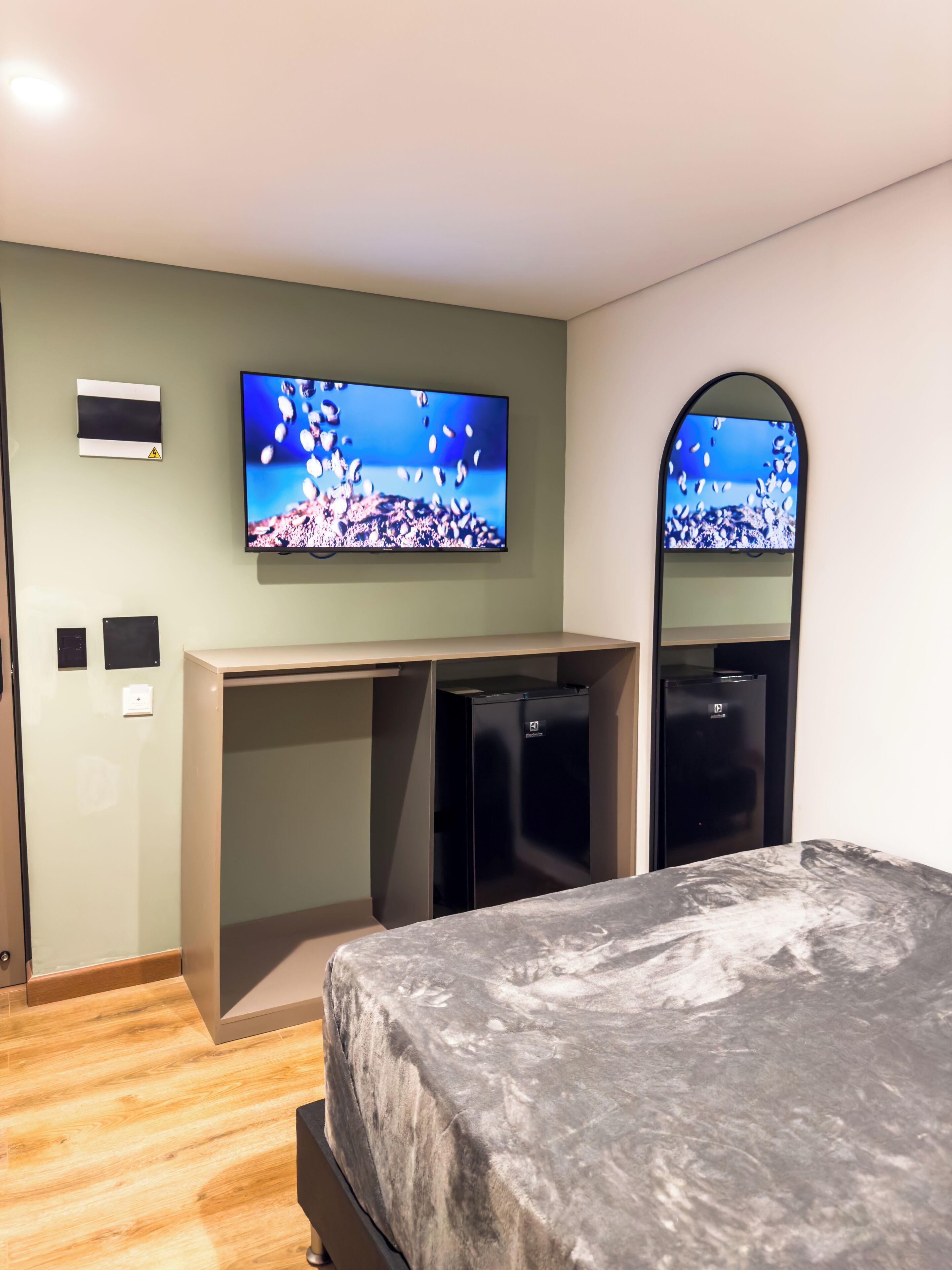 Habitación de hotel con cama, escritorio, televisor y refrigerador.