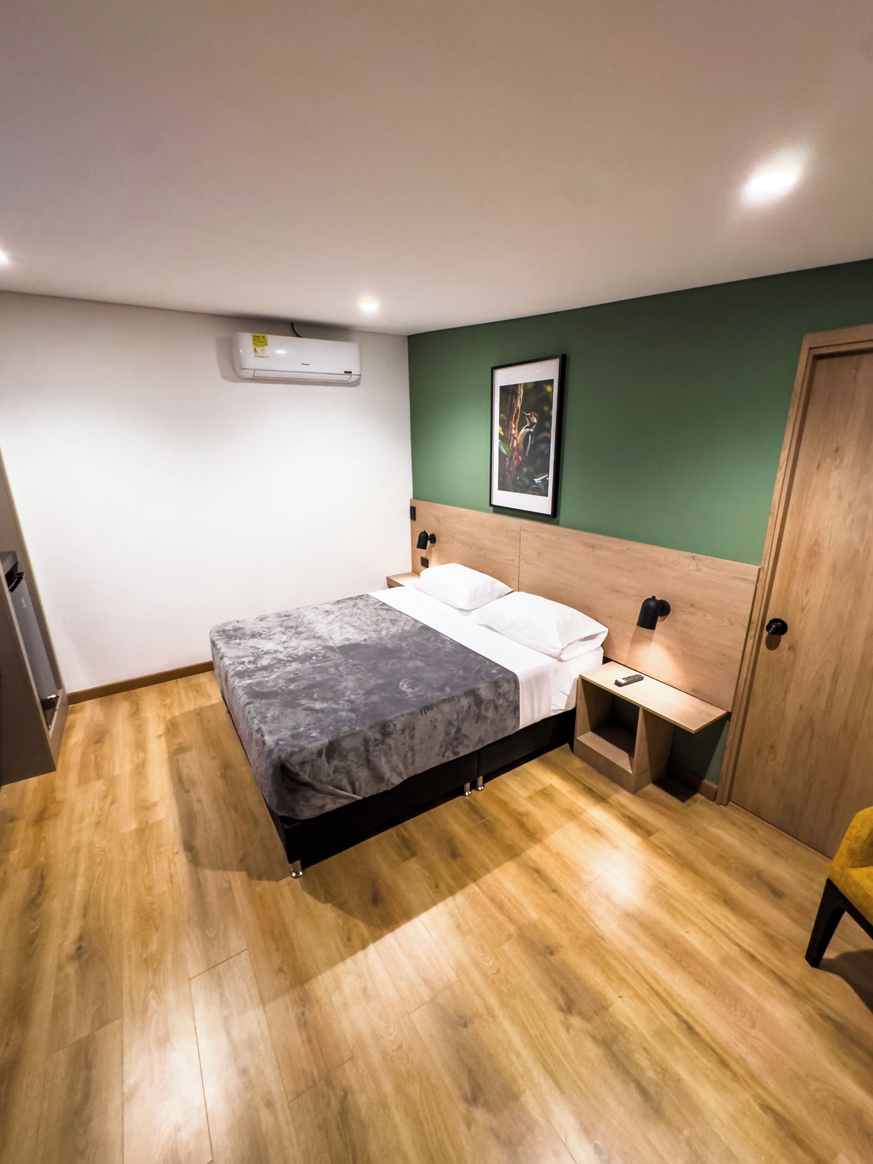A bedroom with a bed, bedside table, nightstand, and a door.
