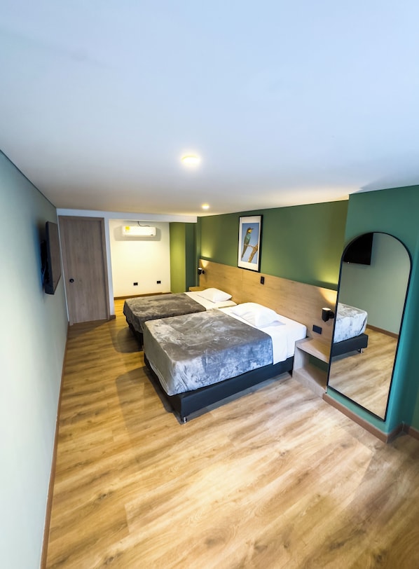A room with a bed, a bedside table, a mirror, and a wall-mounted air conditioner. - Habitat Ochentayuno (Medellín)